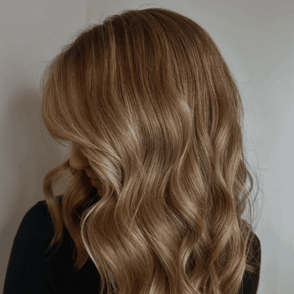 Wavy hair in a soft brown shade, styled with loose curls.