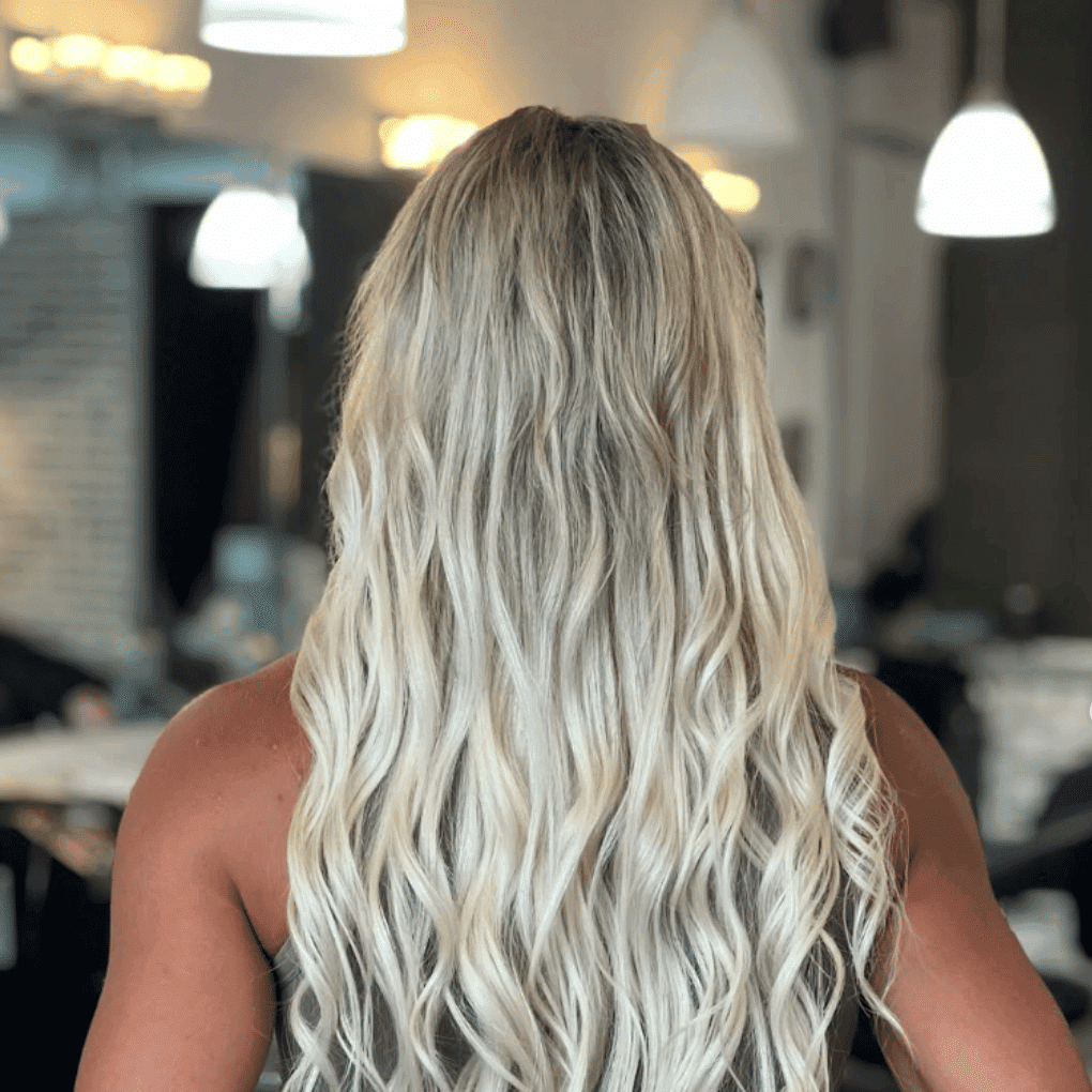Blonde woman with long wavy hair in a modern salon setting.