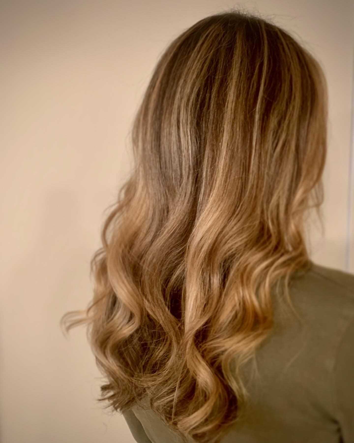 A person with long, wavy, light brown hair seen from the back.